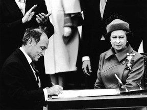 The-prime minister Pierre Trudeau, left, signs the Constitution, Act, 1982, with Queen Elizabeth on April 17, 1982.