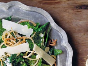 A caper dressing and Parmesan cheese shavings top a kale salad. Deep-fried shallot rings are optional.