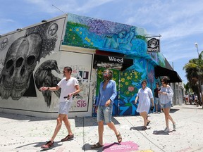 A group of visitors walk by an establishment in the Wynwood area, Aug. 5, 2016, in Miami.