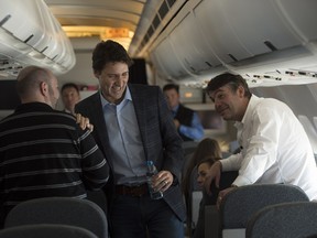 Prime Minister Justin Trudeau shares a laugh with government staff as he makes his way through the cabin of the Airbus to speak to reporters while flying from Antalya, Turkey to Manila, Philippines.