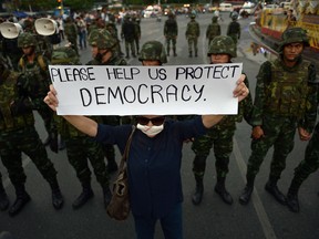An anti-coup protester holds up a sign past soldiers as she takes part in a rally at Victory Monument in Bangkok on May 26, 2014.