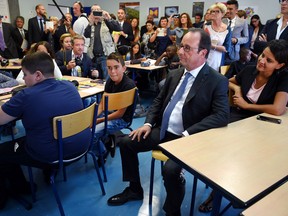 French President Francois Hollande (C) sits with French Minister of Education Najat Vallaud-Belkacem (rear R) in a classroom during a visit at the high school Jean Rostand for the first day of the starting of the school year in Orleans, central France, on September 1, 2016.