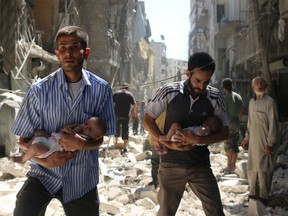 Syrian men carrying babies make their way through the rubble of destroyed buildings following a reported air strike on the rebel-held Salihin neighbourhood of the northern city of Aleppo, on September 11, 2016