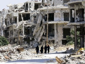 Syrian women walk in between destroyed buildings in the government-held Jouret al-Shiah neighbourhood of the central Syrian city of Homs on September 19, 2016