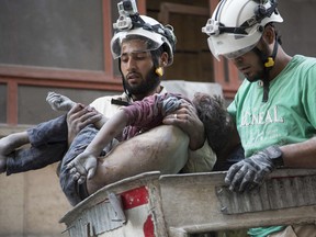 Syrian rescuers hold the body of a girl after pulling it from rubble of a budling following government forces air strikes in the rebel held neighbourhood of Al-Shaar in Aleppo on September 27, 2016