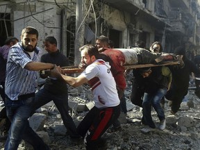 Syrians carry a victim after airstrikes by government helicopters on the rebel-held Aleppo neighbourhood of Mashhad, Syria, Tuesday Sept. 27, 2016.