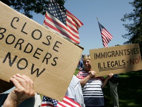 Anti-immigration demonstrators hold signs and American flags during an anti-immigration rally in Santa Clara, Calif., in 2006.