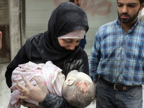 A woman carries the body of her infant following an airstrike Friday on Aleppo blamed on Russian forces.