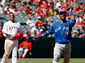 Toronto Blue Jays first baseman Edwin Encarnacion waves his glove at a swarm of bees in the third inning of Toronto's Sept. 18 game against the Los Angeles Angels.