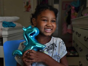 Eden Oyelola, who has an aggressive brain tumor, holds a unicorn coin bank given to her by the Make-a-Wish Foundation.