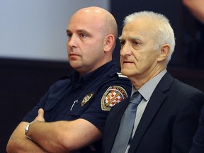 Dragan Vasiljkovic, right, a former Serb military commander sits between guards in a courtroom at the beginning of his trial in Split, Croatia, Tuesday, Sept. 20, 2016.