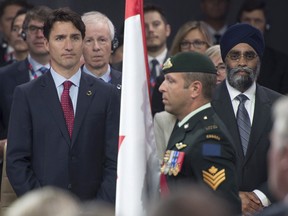 Canadian Prime Minister Justin Trudeau, Foreign Affairs Minister Stephane Dion and Defence Minister Harjit Sajjan stand in front of the Canadian flag during a ceremony at the start of the first plenary session for the NATO summit in Warsaw, Friday July 8, 2016.