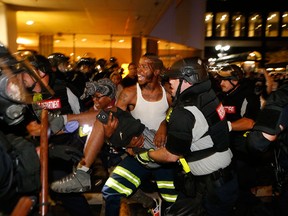 Police and demonstrators carry a seriously wounded protester in Charlotte, N.C., during a Sept. 21, 2016, march to protest the fatal police shooting of Keith Lamont Scott.