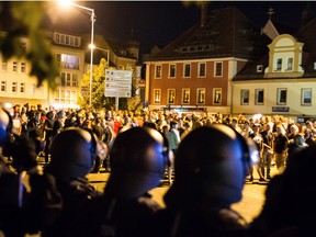 Police officers stand across from right-wing protesters on the square by the Kornmarkt shopping centre in Bautzen, Germany on Thursday, one day after clashes broke out between young migrants and right-wing activists on the square.