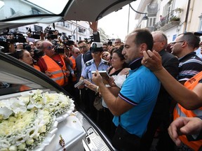 Members of the media crowd around the hearse of Tiziana Cantone as her mother Teresa Giglio, center, salutes it, during her funeral in Casalnuovo, near Naples, Italy, Thursday, Sept. 15, 2016.