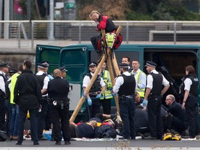 Emergency services surround protestors from the movement Black Lives Matter after they locked themselves to a tripod on the runway at London City Airport in London on September 6, 2016