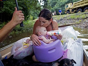 A mother and child wait to be rescued from floodwaters by members of the Louisiana Army National Guard near Walker, La., August 2016