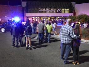 People stand near the entrance on the north side of Crossroads Center shopping mall in St. Cloud, Minn., on Saturday night. Several people were taken to a hospital with injuries after a stabbing attack at the mall, which ended with the suspected attacker dead inside the mall.