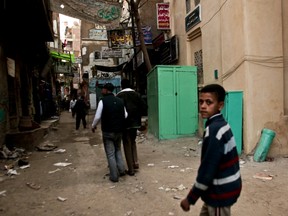 In a 2012 photo, residents of Giza Egypt pass a kiosk, centre, where girls are circumcised by a barber.