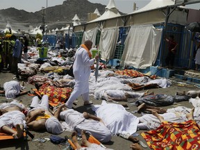 In this Sept. 24, 2015, file photo, a Muslim pilgrim walks through the site where dead bodies are gathered after a stampede during the annual hajj pilgrimage, in Mina, Saudi Arabia.