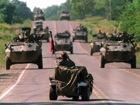 A Mohawk Warrior in a golf cart watches approaching Canadian army armoured vehicles during the 1990 Oka crisis.