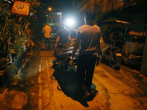 Workers carry the body of a suspected drug dealer after he was killed with two others in a sting operation in the continuing anti-drug campaign of President Rodrigo Duterte early Friday, Sept. 30, 2016, in Caloocan city, north of Manila, Philippines.