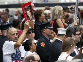 A mourner holds a photo of their loved one during the 15th anniversary of the attacks of the World Trade Center at the National September 11 Memorial, Sunday, Sept. 11, 2016, in New York City