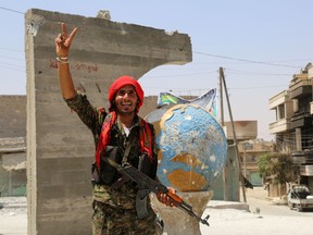 A member of Syrian Democratic Forces (SDF) flashes the sign of victory in the northern Syrian town of Manbij on August 14, more than a week after the SDF, an Arab-Kurdish alliance, pushed the Islamic State group out of the city.