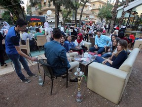 Syrian youths sits at a cafe in the government-held area of the northern Syrian city of Aleppo as they celebrate the Eid al-Adha Muslim holiday on September 13, 2016, a day after a fragile ceasefire was brokered.