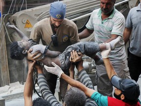 This Tuesday, Sept. 27, 2016 photo shows a Civil Defense worker carrying the body of a child after airstrikes hit al-Shaar neighborhood in Aleppo, Syria.