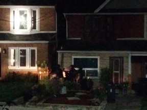 Members of the Emergency Task Force stand by as people leave a house where gunfire was reported