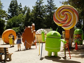 People pose by Android statues at Google's headquarters in Mountain View, Calif.