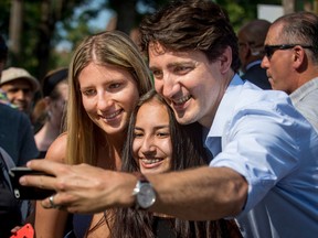 Prime Minister Justin Trudeau takes a selfie with two women at a street festival in Montreal on June 24.