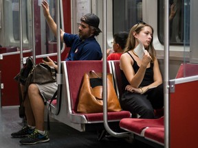 A women fans herself on a 'hot car' while riding the the Bloor-Danforth subway line in Toronto, Ontario, Tuesday, August 30, 2016.