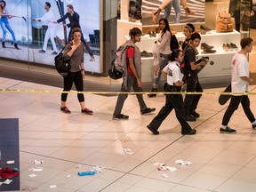 Shoppers pass a crime scene inside the Eaton Centre where a young man was stabbed multiple times in the shopping mall in Toronto, Ontario, Tuesday, September 20, 2016.