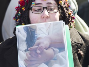 Jennifer Neville-Lake at Marco Muzzo’s sentencing last March. She’s holding a photo of her dying children Harry and Milly holding hands in the hospital. One year after the deaths of her three children and her father, she’s posted a message on Facebook speaking out against drunk driving.