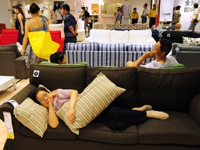 An elderly Chinese (bottom) women rests on a sofa as people shop at an Ikea frurniture store in Beijing on August 15, 2011.