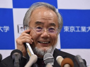 Yoshinori Ohsumi smiles as he speaks with Japanese Prime Minister Shinzo Abe on a phone during a press conference in Tokyo on October 3, 2016, after he was awarded the Nobel Medicine Prize.