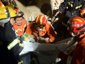 Rescuers carry a young girl who was rescued at an accident site after four buildings caved in during the early hours in Wenzhou, eastern China's Zhejiang province.