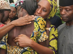 Nigerian Vice President Yemi Osinbajo (right) looks on while his wife Dolapo (centre) comforts one of the 21 freed Chibok girls freed from Boko Haram, on October 13, 2016.