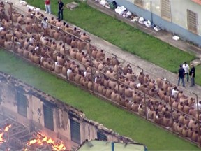 Handout video grab taken from SBT showing inmates sitting in the courtyard of the prison in Franco da Rocha, in the state of Sao Paulo, as several barracks burn in flames on October 17, 2016 when clashes between rival factions in different jails across Brazil left at least 18 inmates dead.