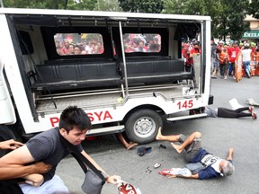 Protesters lie on the ground after being hit by a police van during a rally  in Manila on October 19, 2016
