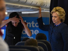US Democratic presidential nominee Hillary Clinton (R) talks to her staff as aide Huma Abedin listens on board their campaign plane at the Westchester County Airport in White Plains, New York, before leaving for campaign rallies on October 28, 2016.