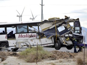 Workers prepare to haul away a tour bus that crashed with a semi-truck in Desert Hot Springs, near Palm Springs, Calif.