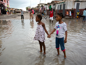 Girls hold hands as they help each other wade through a flooded street after the passing of Hurricane Matthew in Les Cayes, Haiti, Thursday, Oct. 6, 2016.