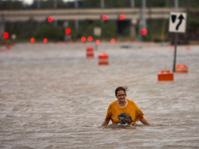 A woman who identified herself as Valerie walks along flooded President Street after leaving her homeless camp after Hurricane Matthew caused flooding, Saturday, Oct. 8, 2016, in Savannah, Ga.