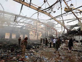 People inspect the aftermath of a Saudi-led coalition airstrike in Sanaa, Yemen, on Saturday, Oct. 8. Yemeni security and medical officials say at least 140 people have been killed in a Saudi-led coalition airstrike that targeted a funeral hall in the capital, Sanaa.