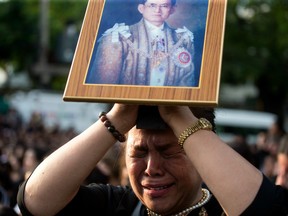 A Thai woman cries and holds a picture of late King Bhumibol Adulyadej while waitiing for a procession of the King's body at the ground outside Grand Palace in Bangkok, Thailand Friday, Oct. 14, 2016.