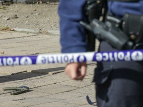 An officer stands near where a man stabbed two police officers. The object at the left, an army multi-purpose eating tool, was found at the scene.