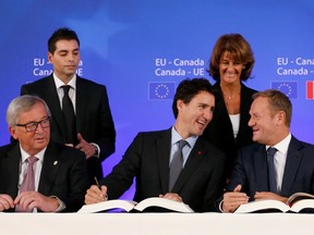Canadian Prime Minister Justin Trudeau, center front, sits with European Commission President Jean-Claude Juncker, left, and European Council President Donald Tusk, right, as they sign the Comprehensive Economic and Trade Agreement (CETA) during an EU-Canada summit at the European Council building in Brussels, Sunday, Oct. 30, 2016.